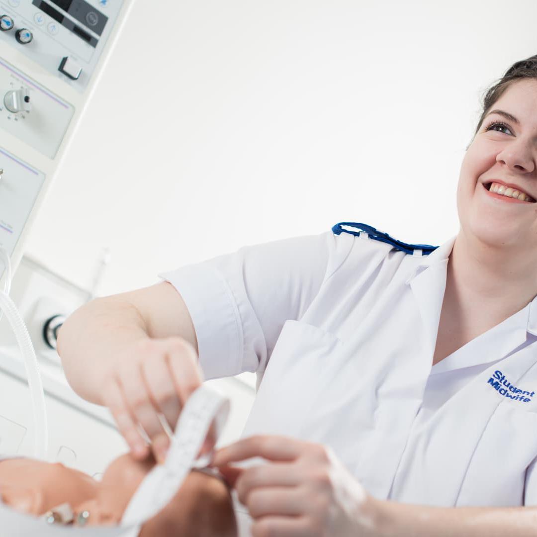 A midwifery student practises on a dummy baby