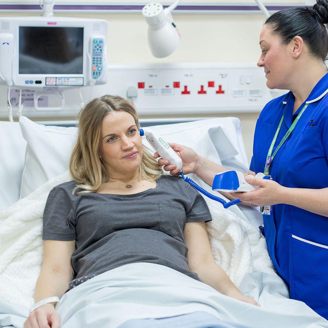 A student midwife stands next to a pregnant patient lying in bed at Hull Women and Children's Hospital