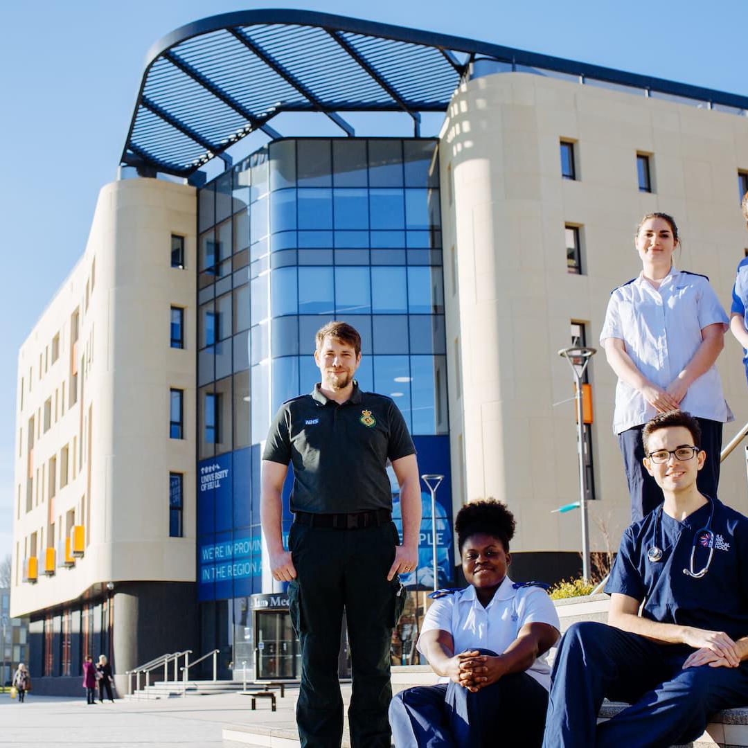 A group of students from different health courses stood outside the Allam Medical Building in uniform 