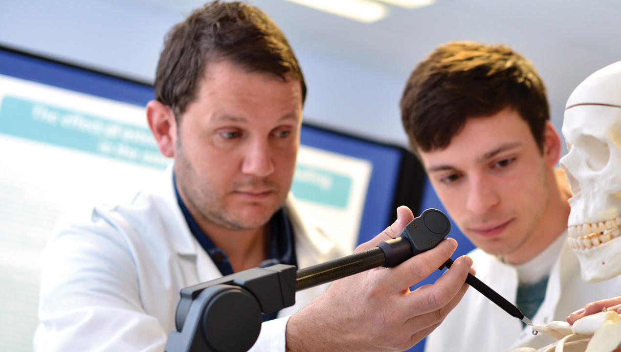 Hull lecturer and student measuring an anatomical model of a human skeleton in the Medical Engineering Lab.