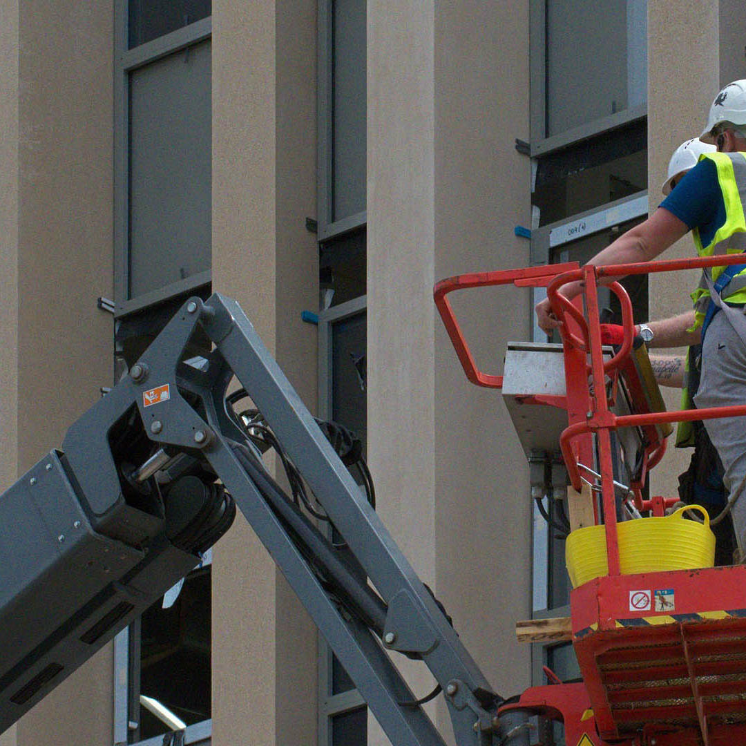 A construction worker in a high vis vest using a cherry picker